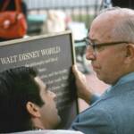 Roy O. Disney holding the dedication plaque.
